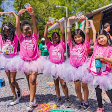 Girls on the Run participants smile while proudly posing and showing off tutus 